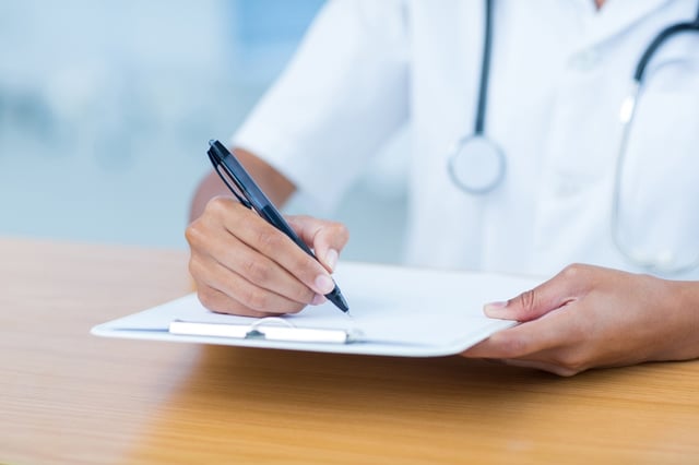 Doctor holding clipboard with file in hospital room.jpeg
