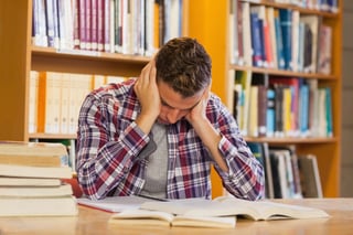 Handsome frustrated student studying his books in library.jpeg